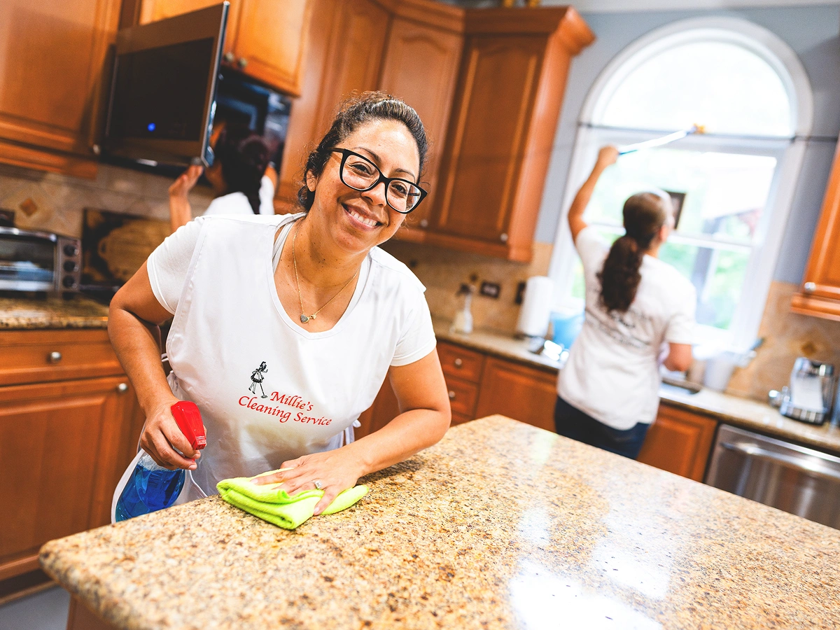 A woman cleaning a kitchen countertop.