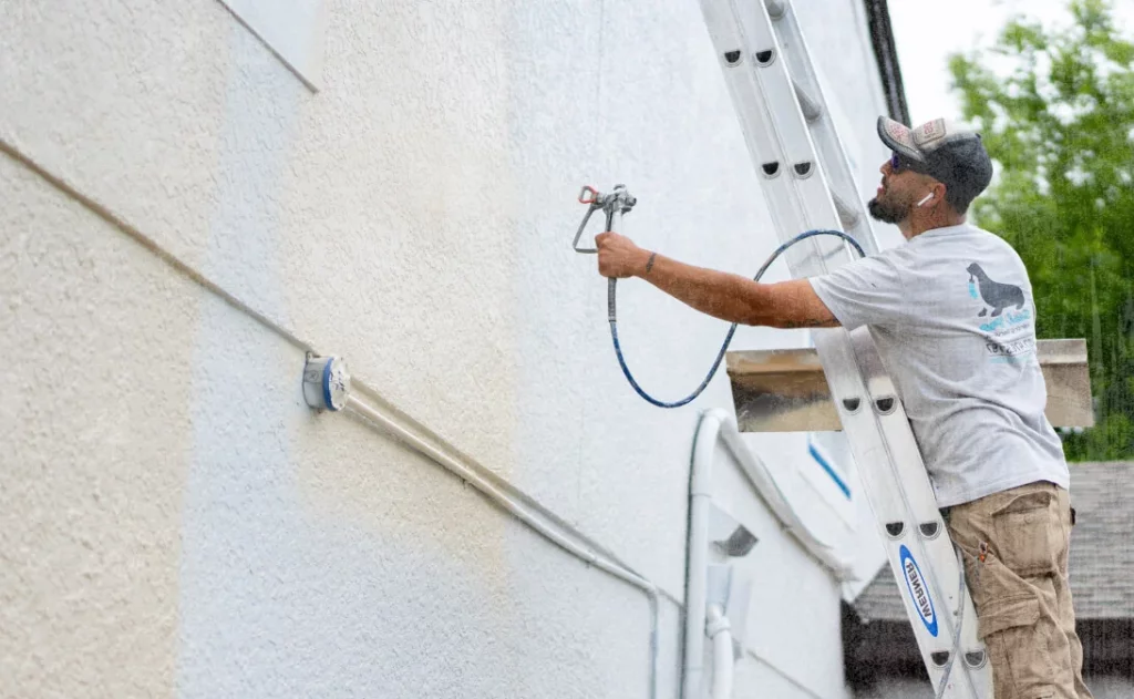 image of painting contractor painting the side of a house after using painting contractor business software