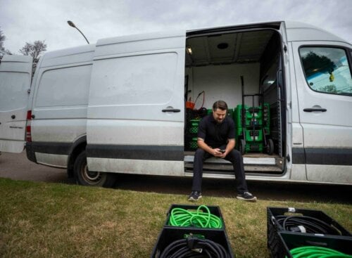 Pest control worker sitting in his van with equipment nearby