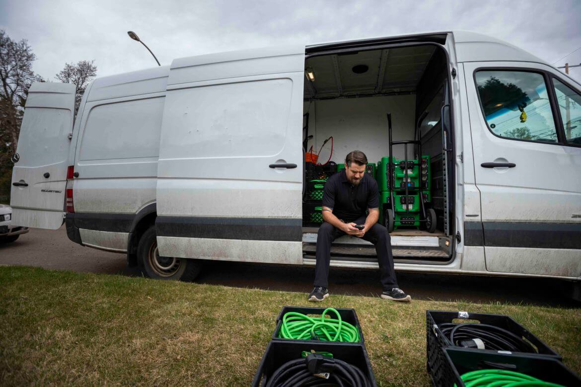 Pest control worker sitting in his van with equipment nearby