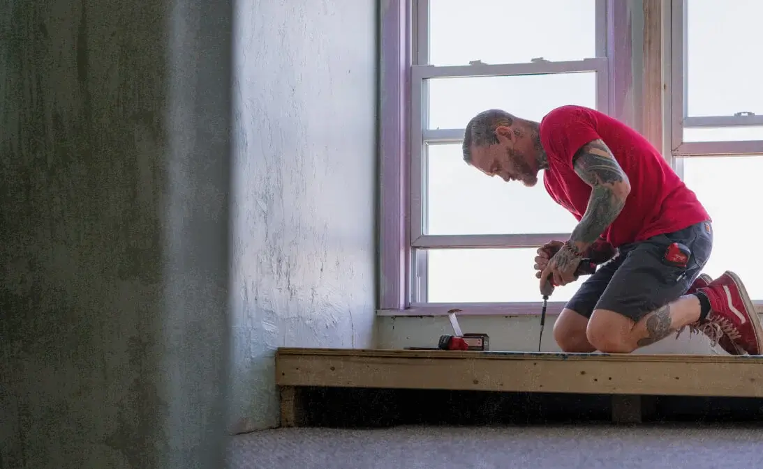 image of handyman drilling down floor after using handyman business software