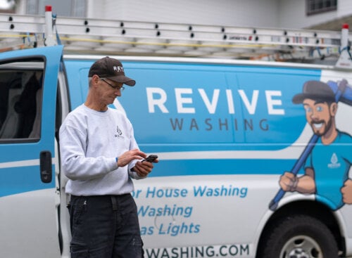 window cleaner standing by work van holding phone