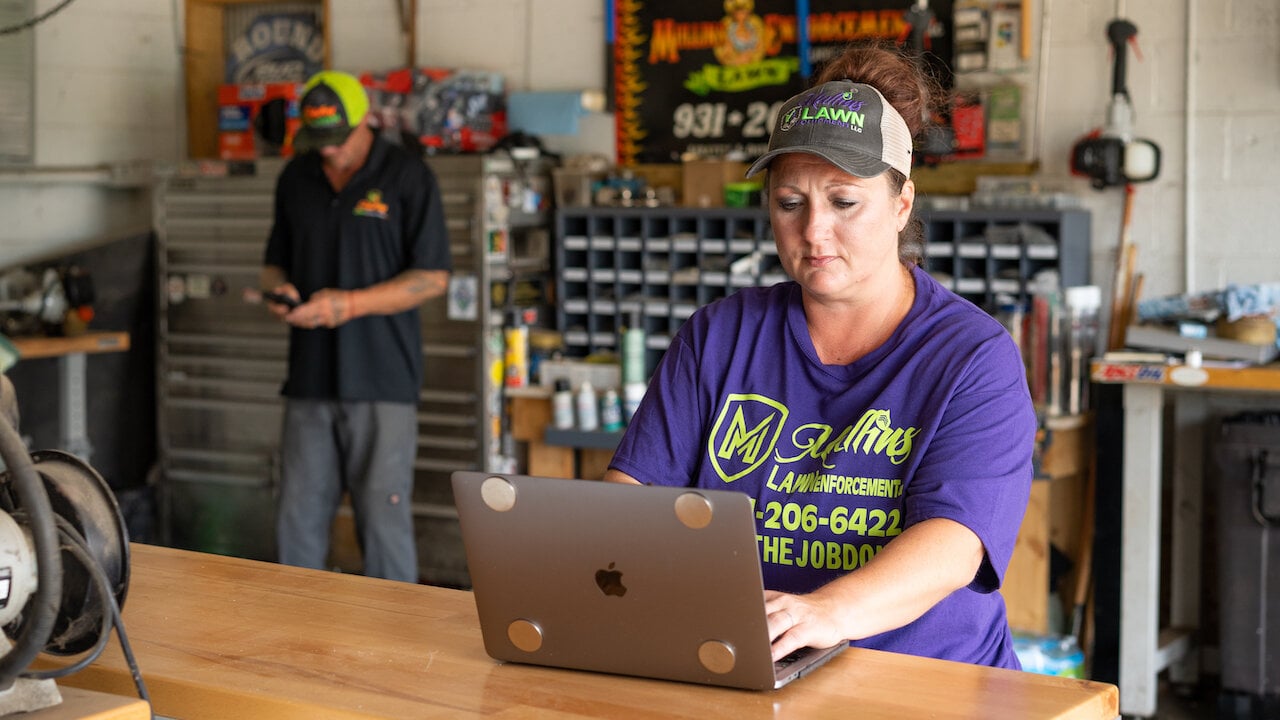 woman typing on laptop in lawn care workspace