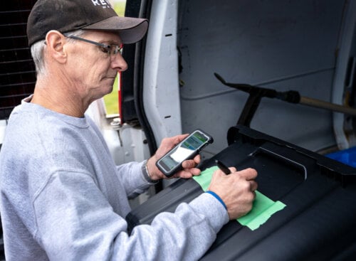 image of pressure washer writing notes and looking at his phone