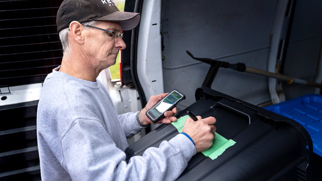 image of pressure washer writing notes and looking at his phone