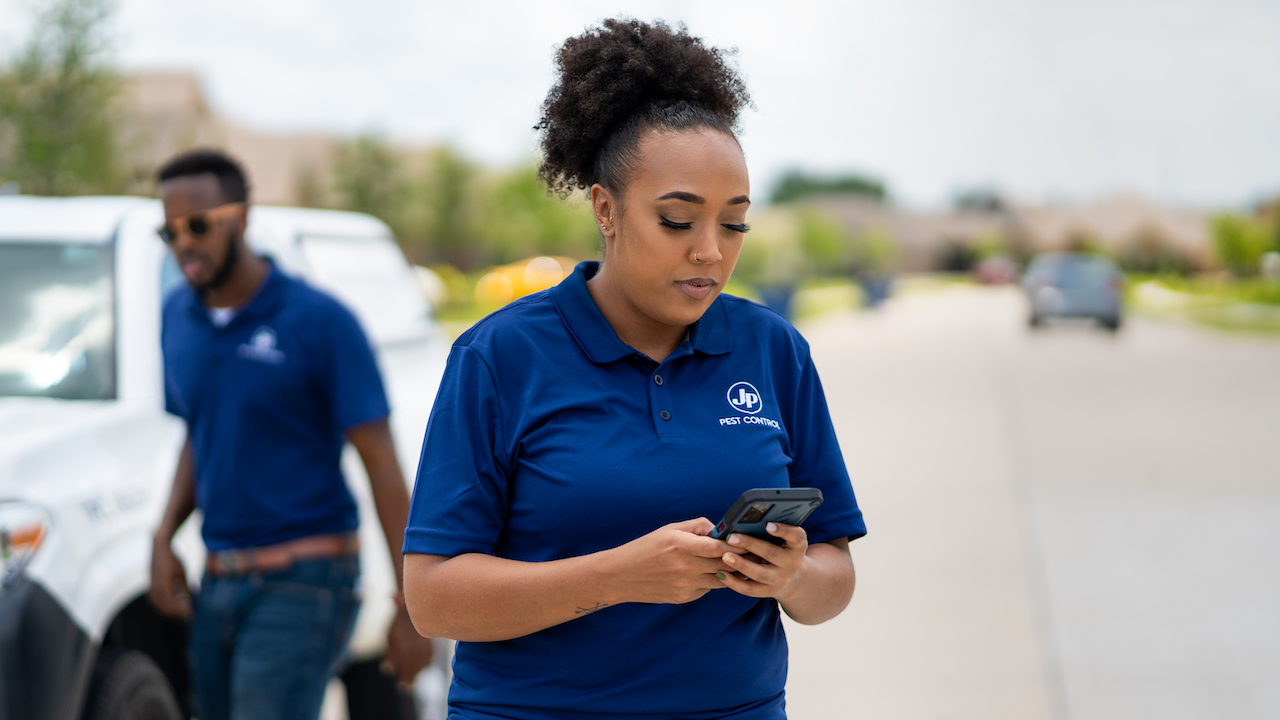 female pest control professional looking at cell phone