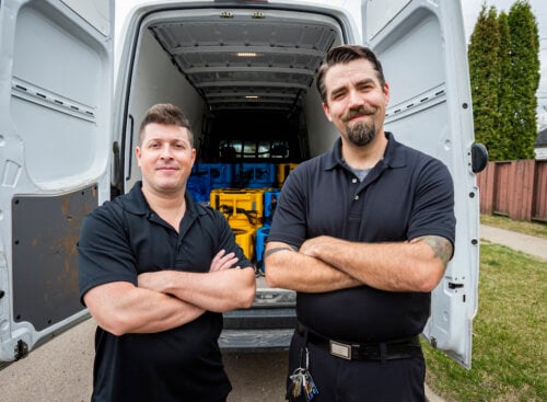 two male workers standing in front of a work truck