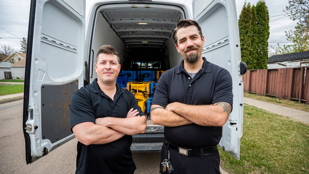 two male workers standing in front of a work truck