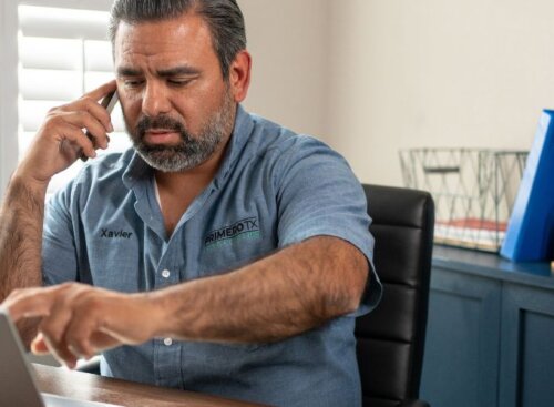 Service provider sits at a desk using a laptop and talking on the phone.