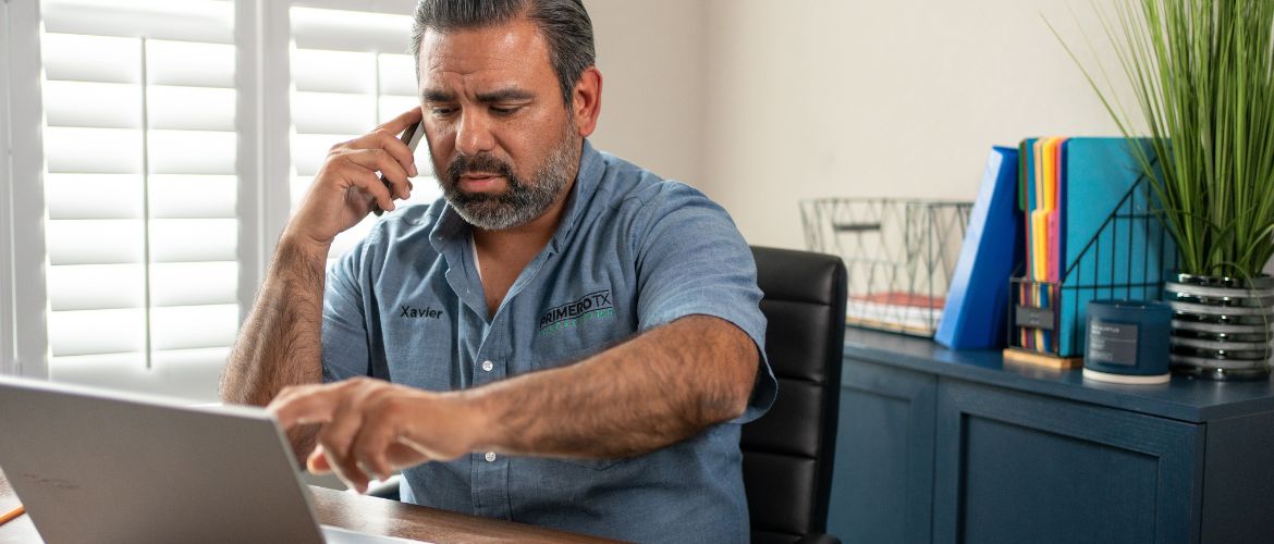 Service provider sits at a desk using a laptop and talking on the phone.