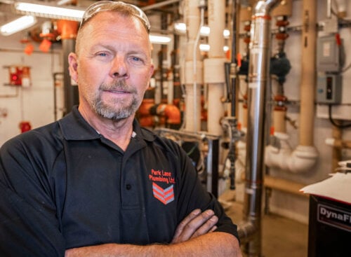 plumber standing in plumbing shop with arms folded