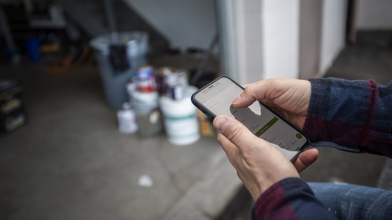 Photo of a painter looking for apps for painting contractors at a jobsite