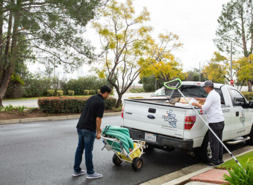 Photo of two pool cleaning contractors loading up a truck with cleaning equipment