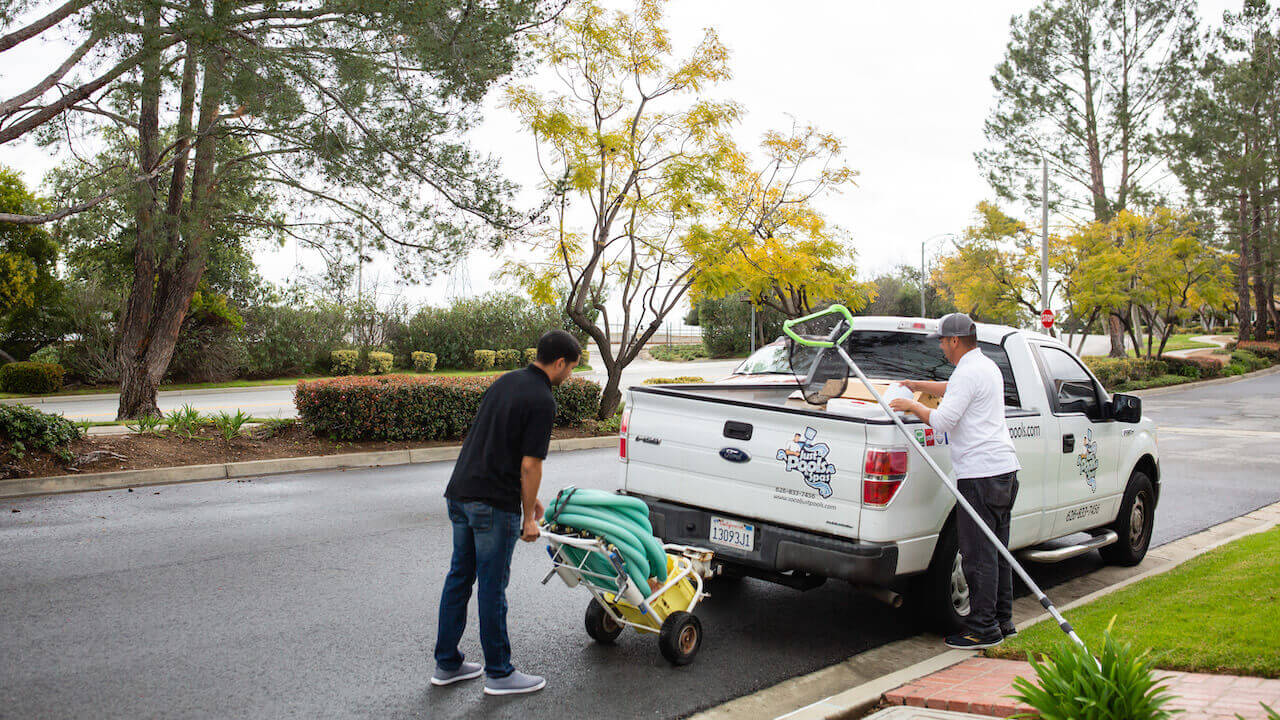 Photo of two pool cleaning contractors loading up a truck with cleaning equipment