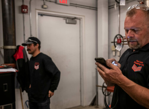 Photo of a service business owner and subcontractor preparing for a job in a maintenance room