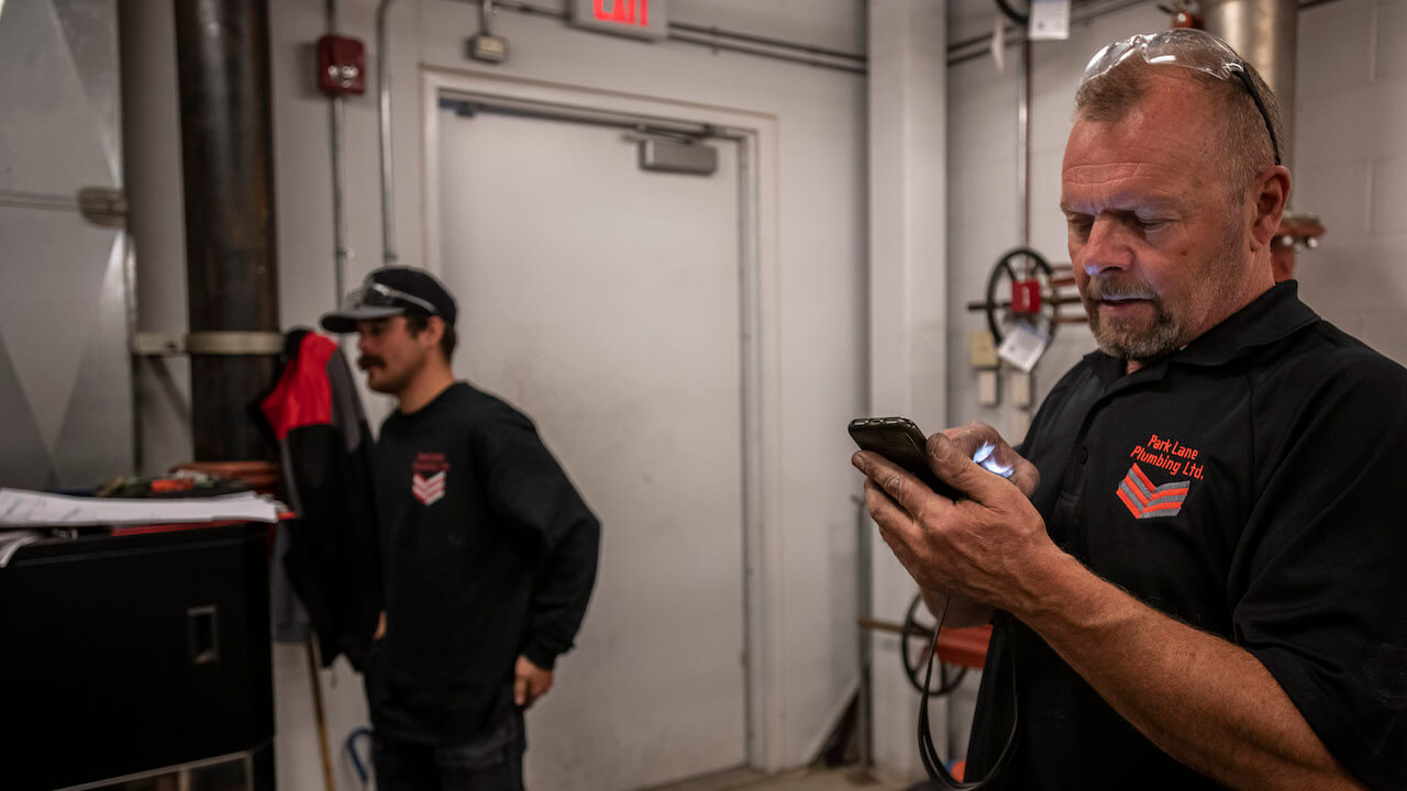 Photo of a service business owner and subcontractor preparing for a job in a maintenance room