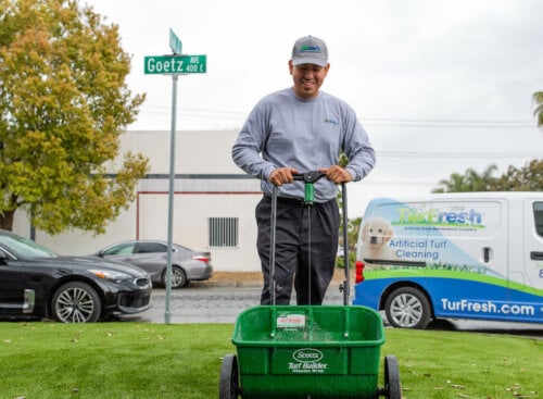 Photo of a lawn care contractor cleaning up a customer lawn with a service van in the background