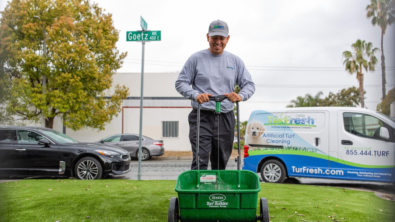 Photo of a lawn care contractor cleaning up a customer lawn with a service van in the background