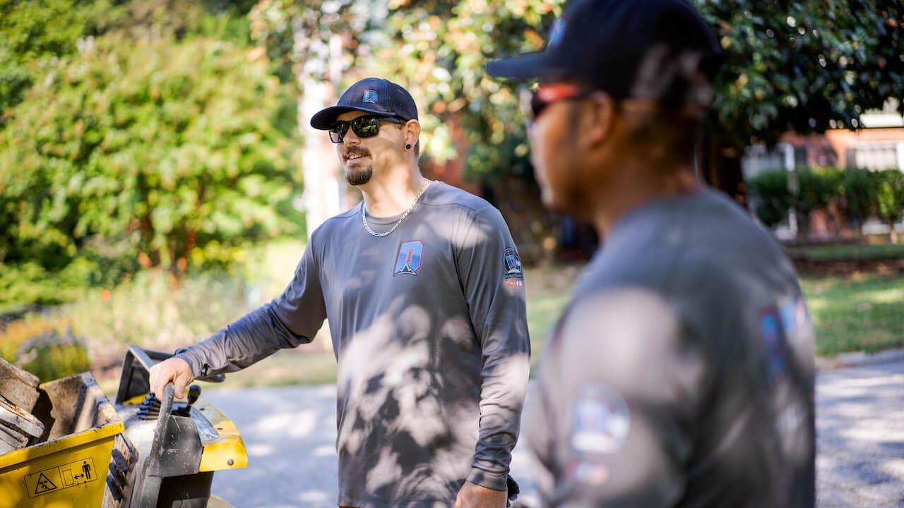 A landscaping business owner and lawn care employee discussing a job outside
