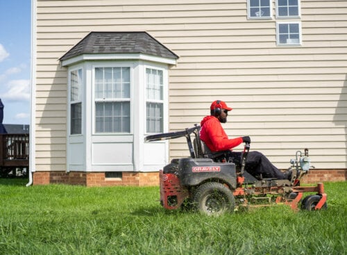 Photo of a lawn care contractor mowing a customer's home lawn on a riding mower