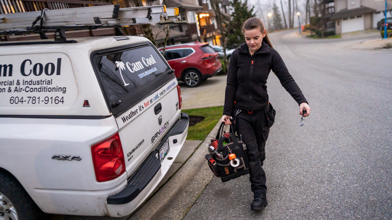 Photo of an HVAC business owner carrying a toolbag to a company truck
