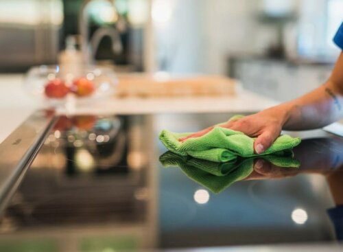 woman cleaning stovetop with cloth