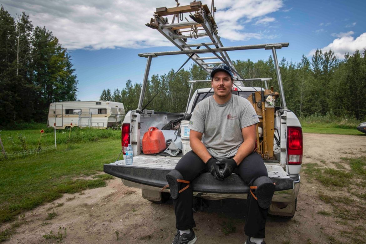 image of roofing service provider sitting on the back of his truck