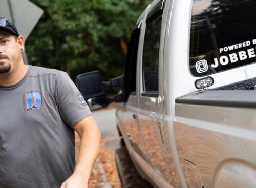 Photo of a landscaping business owner walking past a white pickup truck