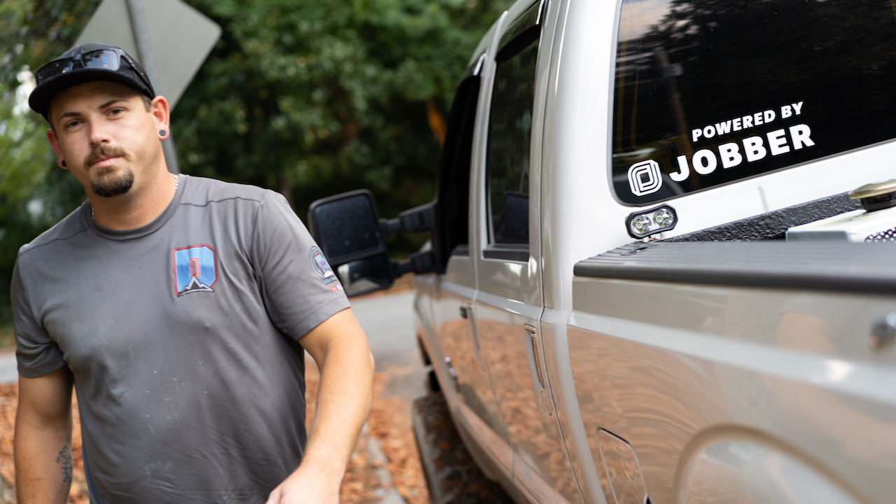 Photo of a landscaping business owner walking past a white pickup truck