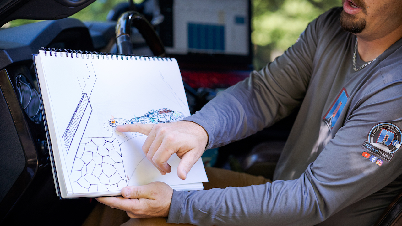 Photo of a landscaping contractor sitting in a truck and pointing at a drawing of a client's landscape