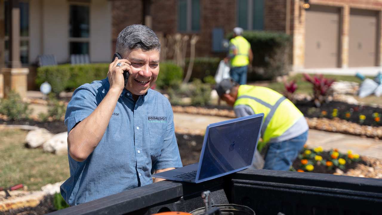Photo of a landscaping business owner at a client's property phoning a lead from his landscaping website