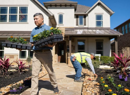Two landscaping contractors moving flower beds and installing rocks on a client's front lawn
