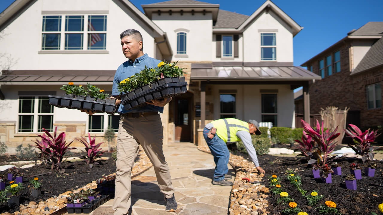 Two landscaping contractors moving flower beds and installing rocks on a client's front lawn