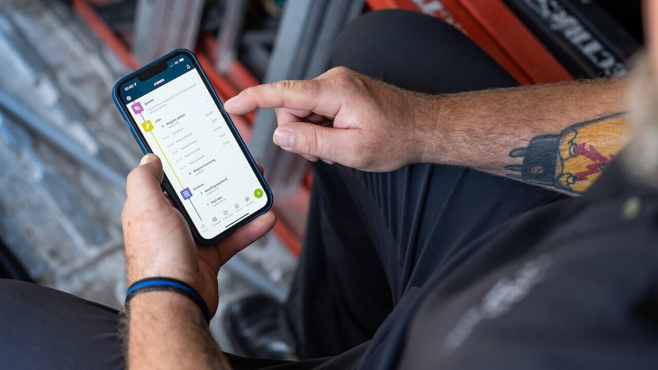 Photo of a service business owner accessing customer payments online on the Jobber mobile app