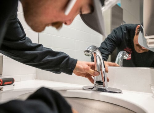 image of plumber installing faucet