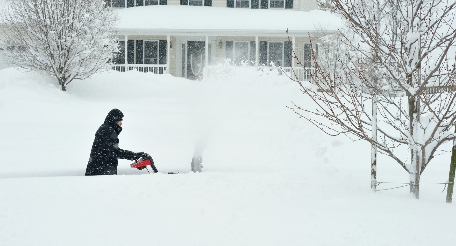 image of a man snow blowing a sidewalk