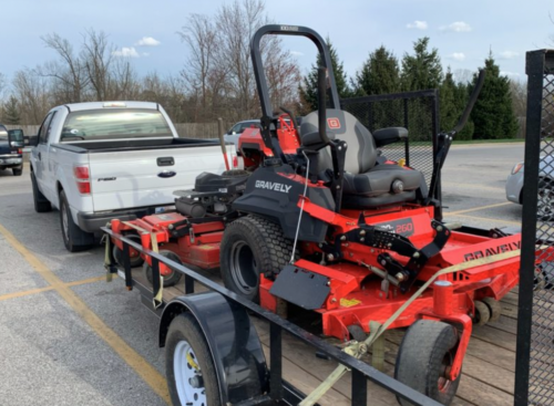 Photo of a lawn tractor owned by Lawn Squad being hauled by a pickup truck in a parking lot