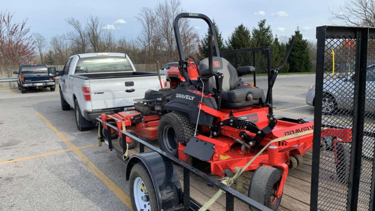 Photo of a lawn tractor owned by Lawn Squad being hauled by a pickup truck in a parking lot