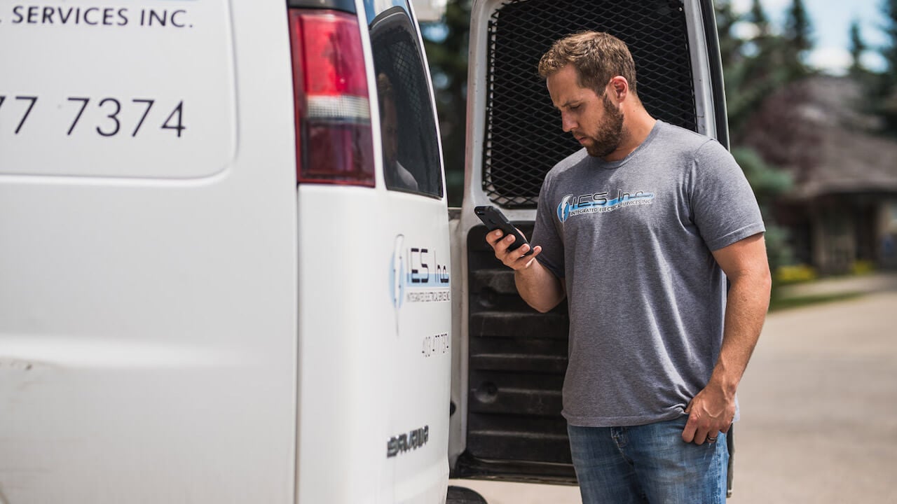 Photo of a contractor scheduling his crew on a smartphone using route optimization