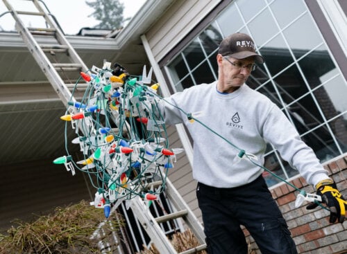 Contractor doing Christmas lights installation on a client's house as a winter landscaping service
