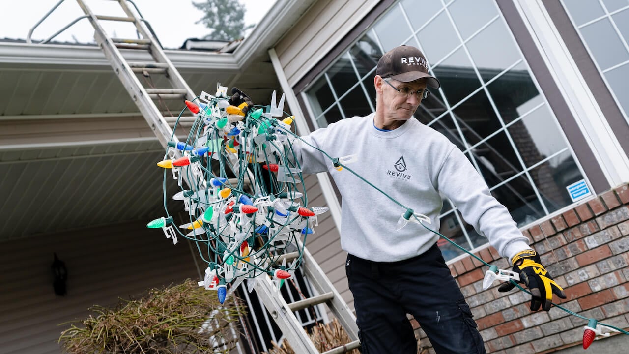 Contractor doing Christmas lights installation on a client's house as a winter landscaping service