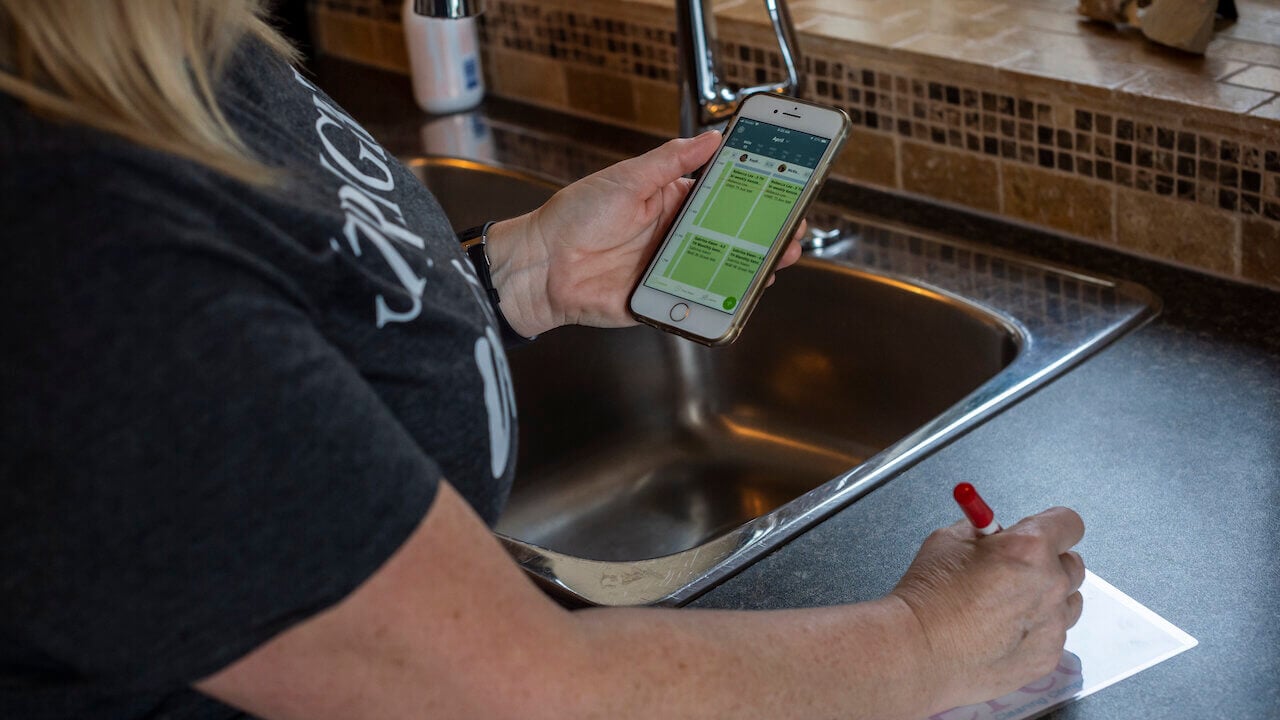 cleaner looking at schedule on phone and filling out a paper form