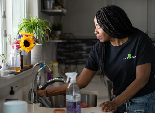woman cleaning kitchen sink and counters