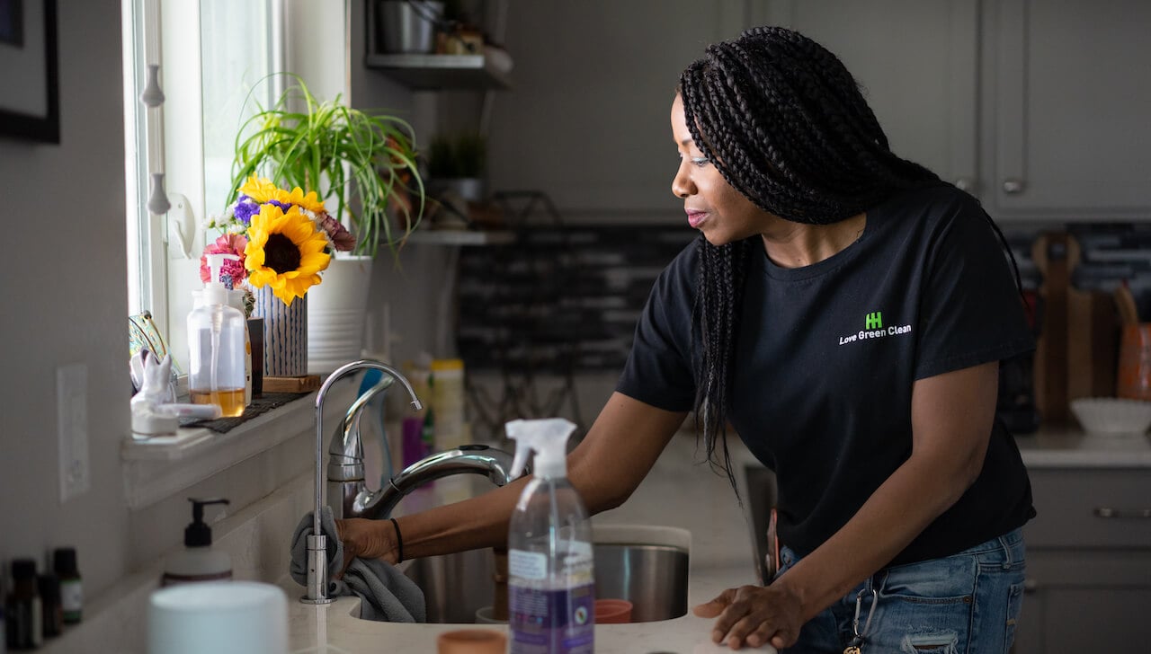 woman cleaning kitchen sink and counters