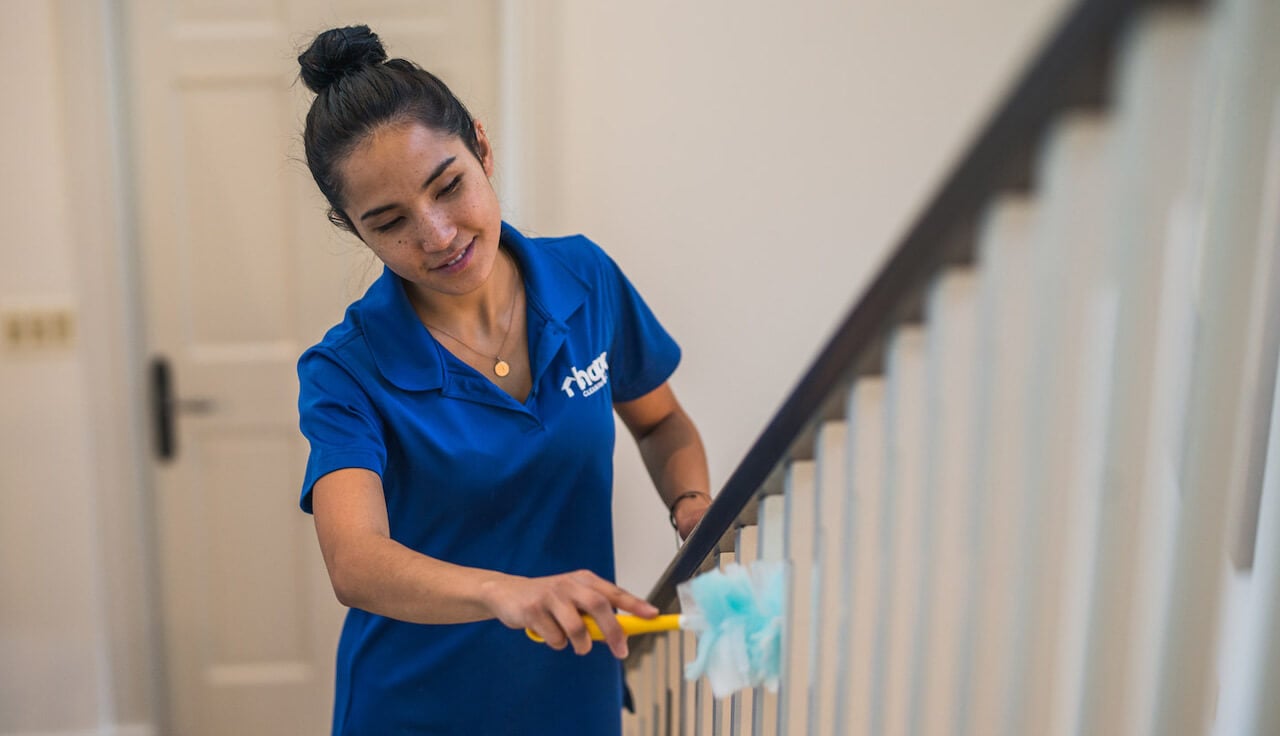woman feather dusting banister