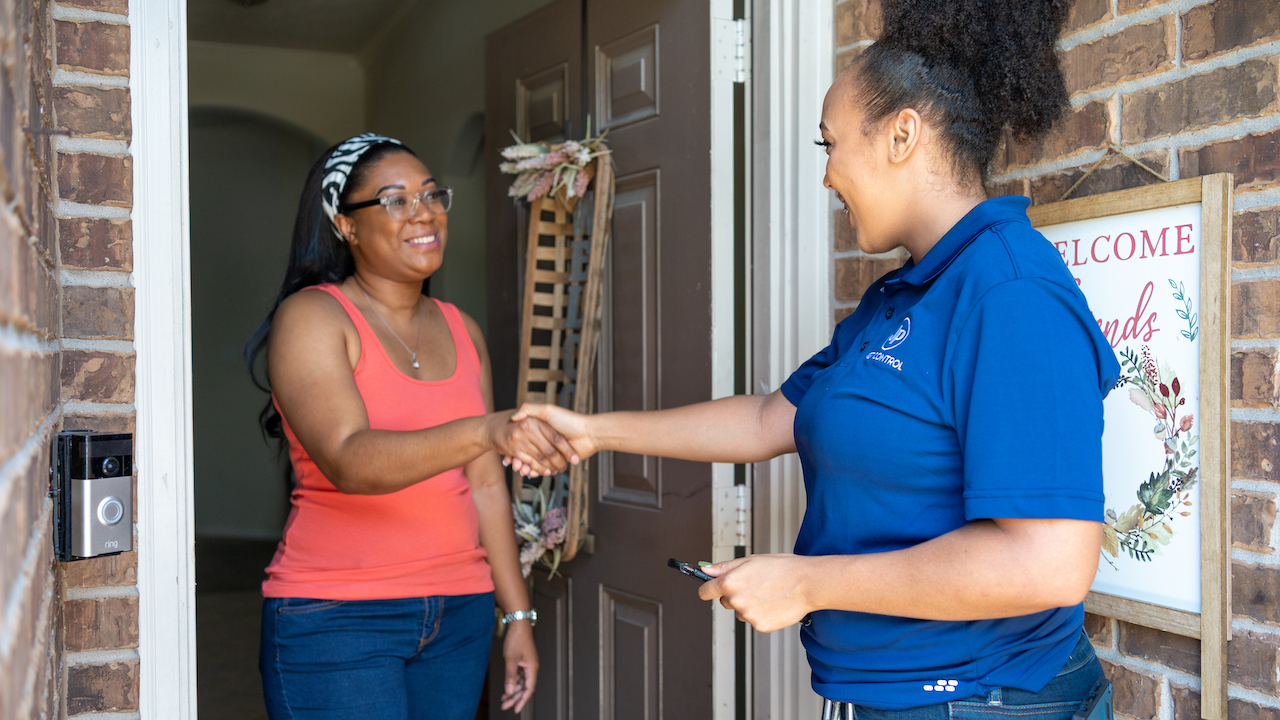 two women standing at the front door of a home, shaking hands