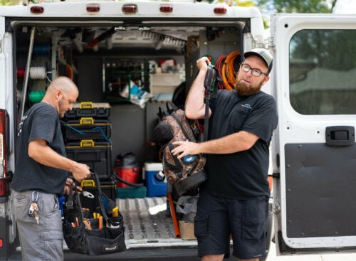 image of electricians pulling equipment off of work van