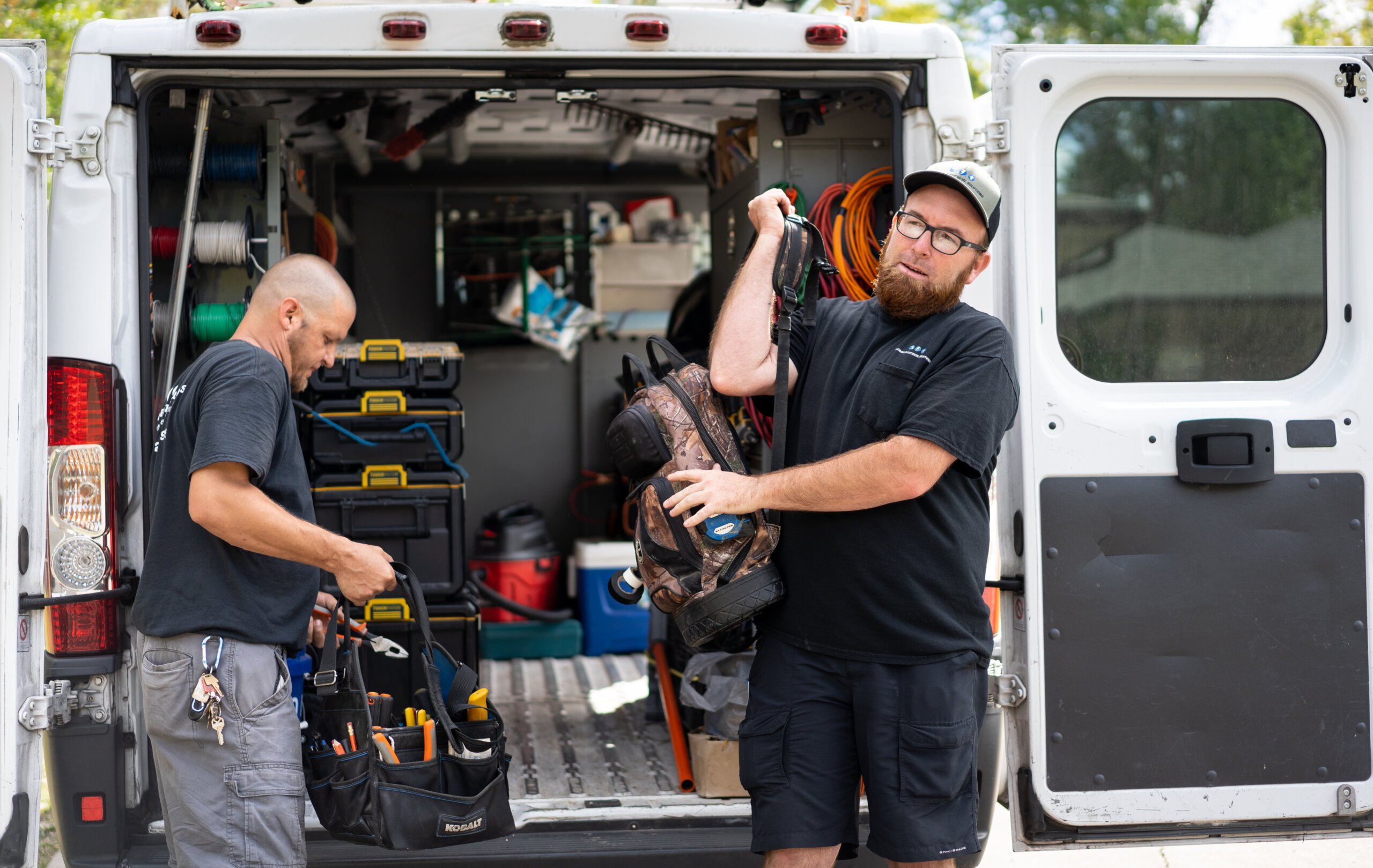 image of electricians pulling equipment off of work van