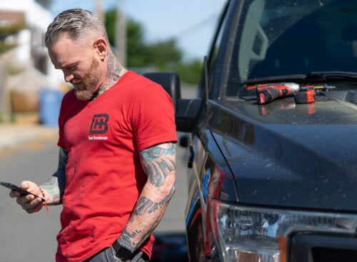 man standing by truck looking at his phone