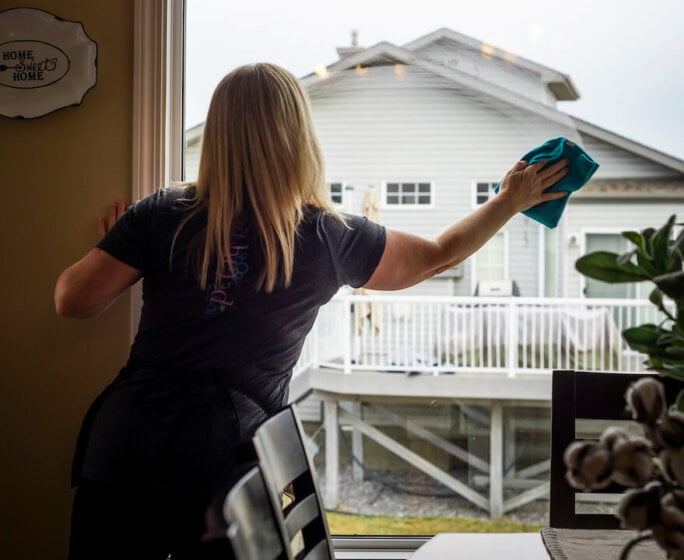 woman cleaning dining room window